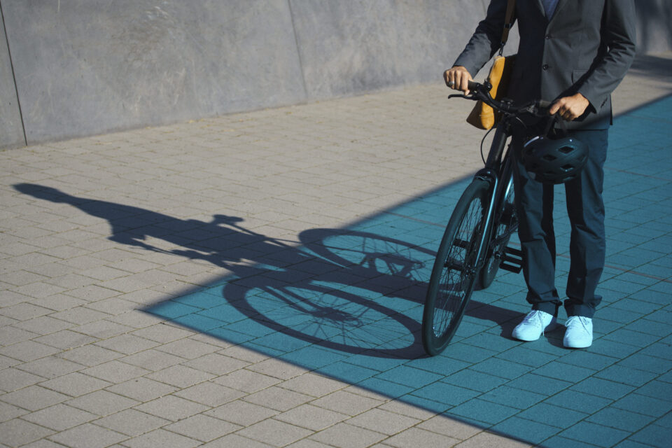 Elektro-Autos und E-Bikes werden über eine App gebucht Ein Mann im Anzug schiebt ein Fahrrad